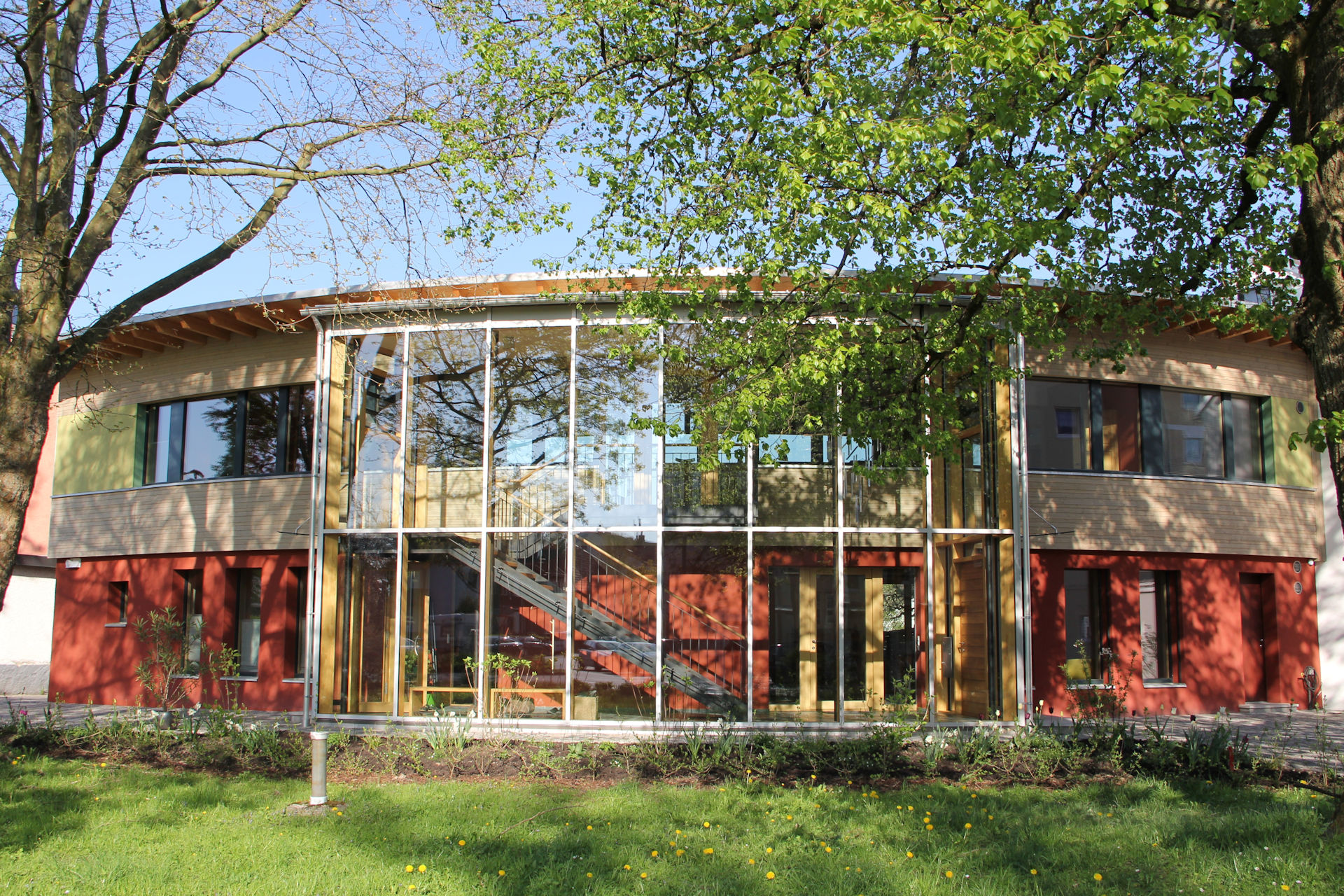 Rot-gelbe Frontansicht des modernisierten Instituts für Baubiologie mit Glasfront