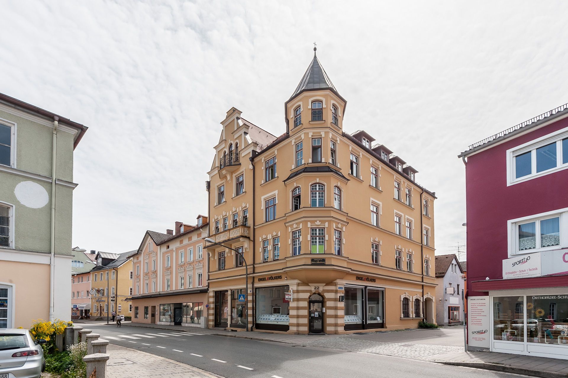 Frontansicht eines an einer Straßenkreuzung stehenden Wohn- und Geschäftshauses in Rosenheim, das durch energetische Sanierung modernisiert wurde