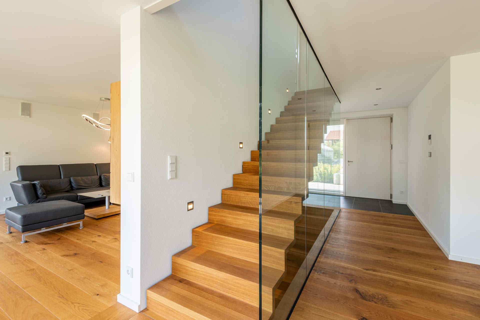 Treppenaufgang eines Wohnhauses aus hellem Holz mit Glasbegrenzung